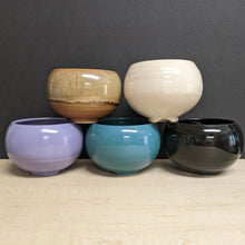 Load image into Gallery viewer, Five round glossy ceramic cauldrons in varying colors on a black background. The colors from left to right top to bottom are light brown, white, purple, blue, and black.
Sold at Coyote Supply Co a BIPOC and LGBTQIA+ owned zero waste witch store in Reno Nevada