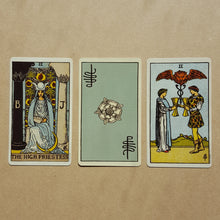 Load image into Gallery viewer,  Three tarot cards, left to right:  The High Priestess, a back of a card featuring Pixie&#39;s signature and a white Tudor style rose on light blue, two of cups.