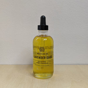 Glass bottle with black dropper lid containing golden multi use oil by Motherland Essentials reads "lavender sage" in black block letters available at Coyote Supply Co, a zero waste witch store in Midtown Reno, Nevada that is BIPOC owned