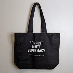 Black tote bag reads "Compost White Supremacy" in white block letters available at Coyote Supply Co, a zero waste witch store in Midtown Reno, Nevada that is BIPOC owned
