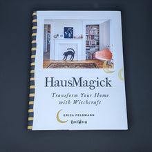 Load image into Gallery viewer, White book by Erica Feldmann of HausWitch  features a colorful photo of a living room and reads &quot;HausMagick&quot; in black block letters available at Coyote Supply Co, a zero waste witch store in Midtown Reno, Nevada that is BIPOC owned