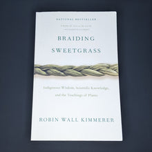Load image into Gallery viewer, White book by Robin Wall Kimmerer features a photo of a sweetgrass braid and reads &quot;Braiding Sweetgrass&quot; in green serif letters available at Coyote Supply Co, a zero waste witch store in Midtown Reno, Nevada that is BIPOC owned