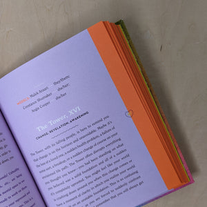 Inside of the guidebook for the Queer Tarot by Ash + Chess. Purple page with orange edge features black lettering.
