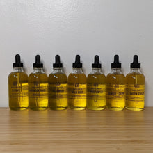 Load image into Gallery viewer, Seven glass bottles filled with golden multi-use oil by Motherland Essentials available at Coyote Supply Co, a zero-waste witch store in Midtown Reno, Nevada that is BIPOC owned