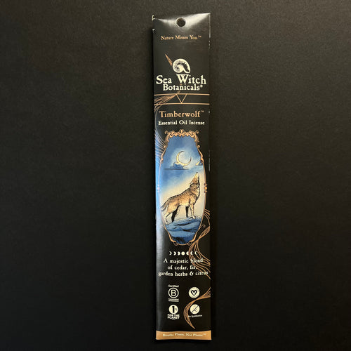 A glossy black cardboard envelope with brown embellishments. The envelope has an illustration of a wolf howling at a crescent moon. 
The envelope reads, 