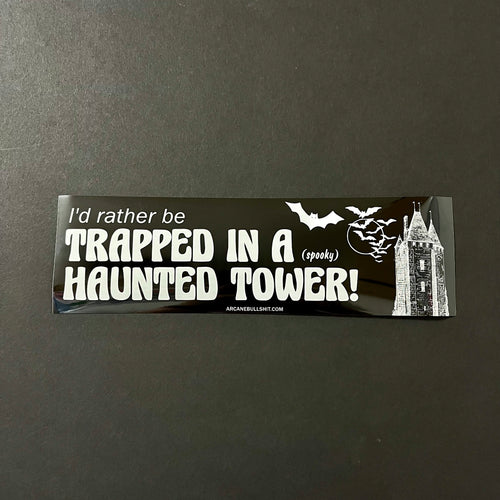 A black bumper sticker with bats, a tower, and white text that reads: I'd rather be trapped in a (spooky) haunted tower!  Sold at Coyote Supply Co a BIPOC and LGBTQIA+ owned zero waste witch store in Reno Nevada 