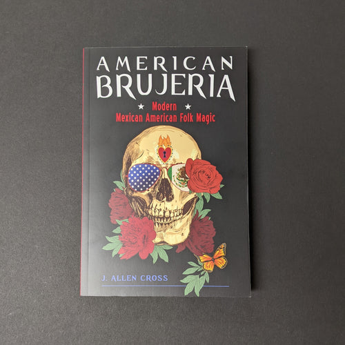 A black book cover that reads American Brujeria Modern Mexican American Folk Magic by J. Allen Cross. The cover also has an image of a skull wearing aviator style sunglasses with the Mexican and American flag in the lenses surrounded by roses. Sold at Coyote Supply Co a BIPOC and LGBTQIA+ owned zero waste witch store in Reno Nevada