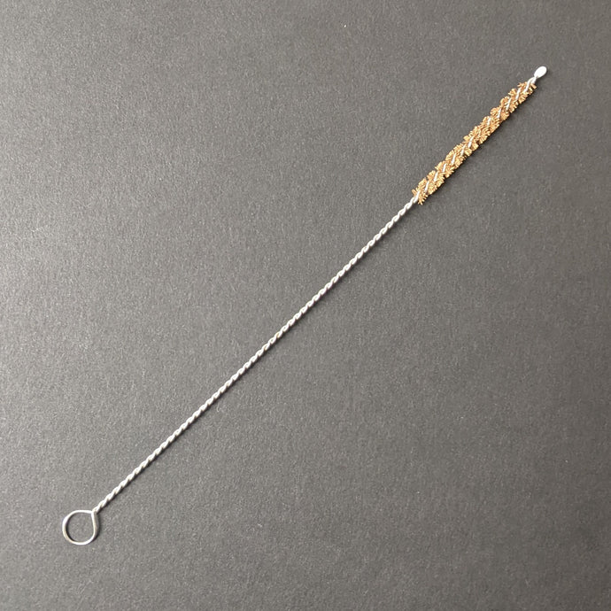A boba straw brush comprised of a twisted metal and natural brown bristles on a black background.  Sold at Coyote Supply Co a BIPOC and LGBTQIA+ owned zero waste witch store in Reno Nevada 