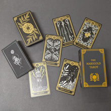 Load image into Gallery viewer, Black background with tarot deck scattered on it.  Cards, box, and guide book are gold and white skeletons and botanicals on black paper.  Sold at Coyote Supply Co a BIPOC and LGBTQIA+ owned zero waste witch store in Reno Nevada
