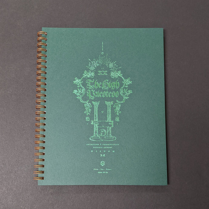 A green spiral bound note book with green foil details. The cover reads The High Priestess and has illustrations of vines and two columns. 
Sold at Coyote Supply Co a BIPOC and LGBTQIA+ owned zero waste witch store in Reno Nevada 