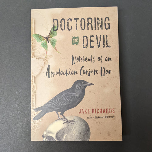 A tan book cover with images of a moth and crow atop a skull that reads Doctoring the Devil Notebooks of an Appalachian Conjure Man by Jake Richards. Sold at Coyote Supply Co a BIPOC and LGBTQIA+ owned zero waste witch store in Reno Nevada