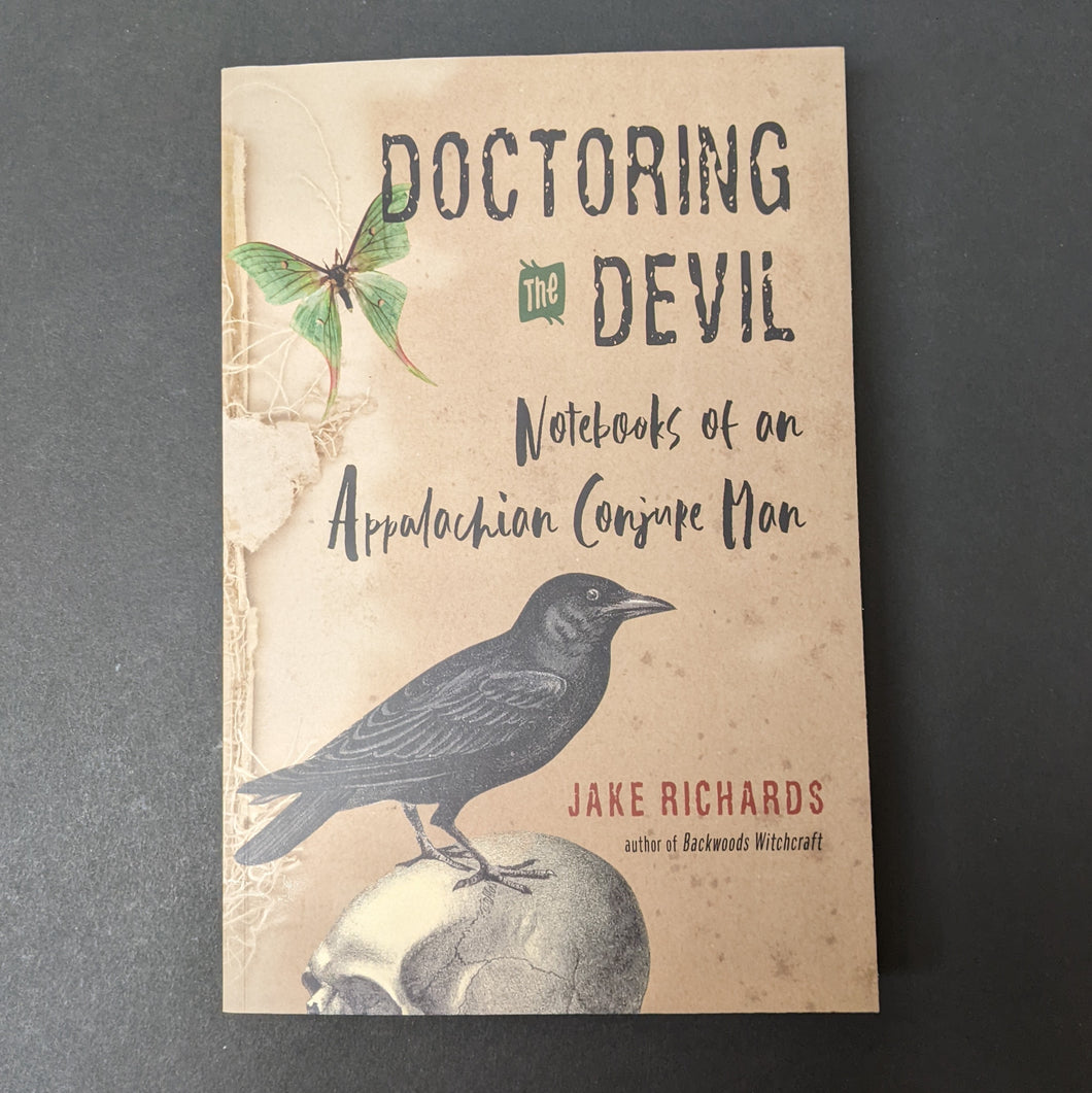 A tan book cover with images of a moth and crow atop a skull that reads Doctoring the Devil Notebooks of an Appalachian Conjure Man by Jake Richards. Sold at Coyote Supply Co a BIPOC and LGBTQIA+ owned zero waste witch store in Reno Nevada