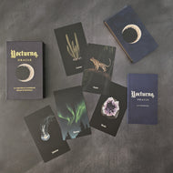 An assortment of cards from the Nocturna Oracle alongside the rest of the deck, the deck box, and the guide book on a black background. 
Sold at Coyote Supply Co a BIPOC and LGBTQIA+ owned zero waste witch store in Reno Nevada