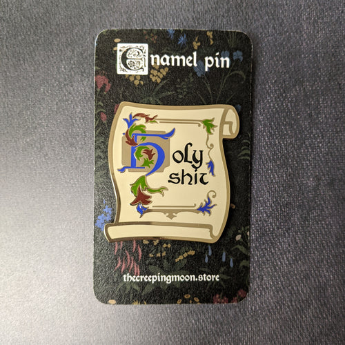 An enamel pin styled like an unrolled piece of parchment that reads 