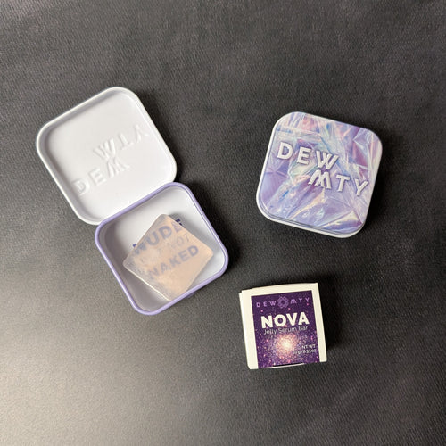 The DEW MTY Nova jelly serum bar alongside it's packaging options of a paper wrap or metal case in purple. Sold at Coyote Supply Co a BIPOC and LGBTQIA+ owned zero waste witch store in Reno Nevada