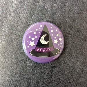 A glossy purple button with white stars and a black witch hat with a dark purple band illustration. The band of the at says "Resist" in whimsical white text.
Sold at Coyote Supply Co a BIPOC and LGBTQIA+ owned zero waste witch store in Reno Nevada