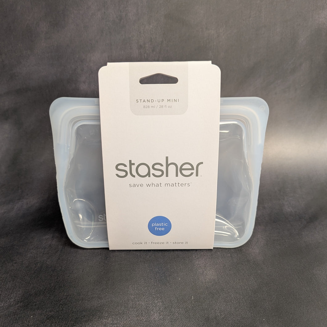 A clear silicone standing bag with a white cardboard band around it. The band has grey text that reads:
STAND-UP MINI
828ml / 28 fl oz
stasher
save what matters
plastic free
cook it freeze it store it