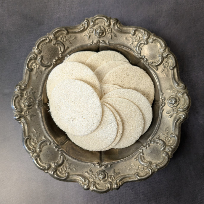 A vintage plate with a stack of white loofah rounds. Sold at Coyote Supply Co a BIPOC and LGBTQIA+ owned zero waste witch store in Reno Nevada