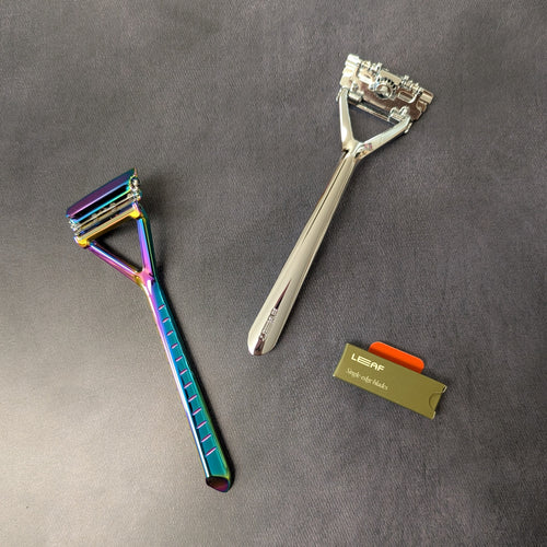 Two plastic free Leaf Shave pivoting head triple blade razors and a pack of single edge blades. One razor is an iridescent chrome and the other is a silver polished metal. Sold at Coyote Supply Co a BIPOC and LGBTQIA+ owned zero waste witch store in Reno Nevada