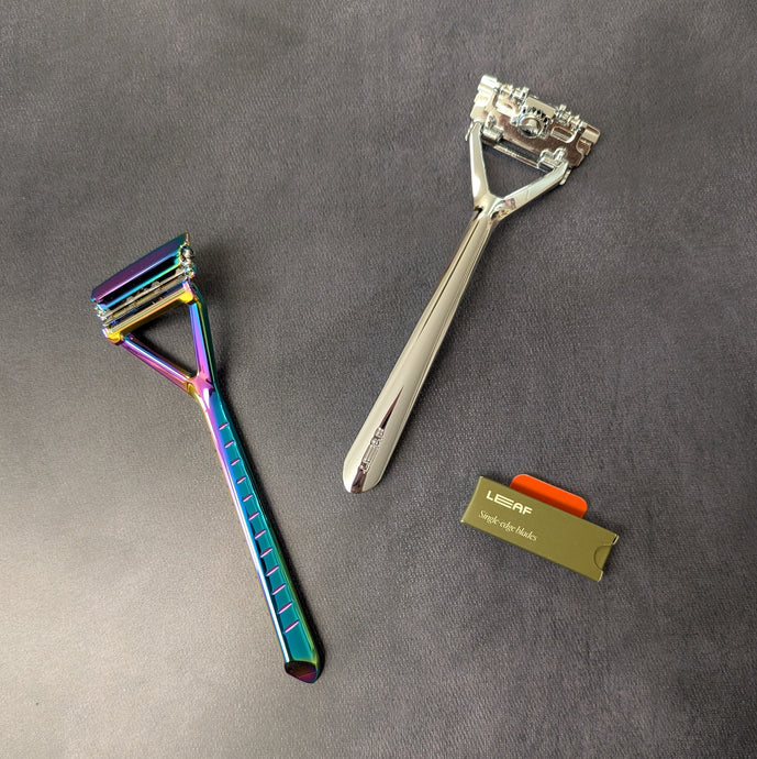 Two plastic free Leaf Shave pivoting head triple blade razors and a pack of single edge blades. One razor is an iridescent chrome and the other is a silver polished metal. Sold at Coyote Supply Co a BIPOC and LGBTQIA+ owned zero waste witch store in Reno Nevada