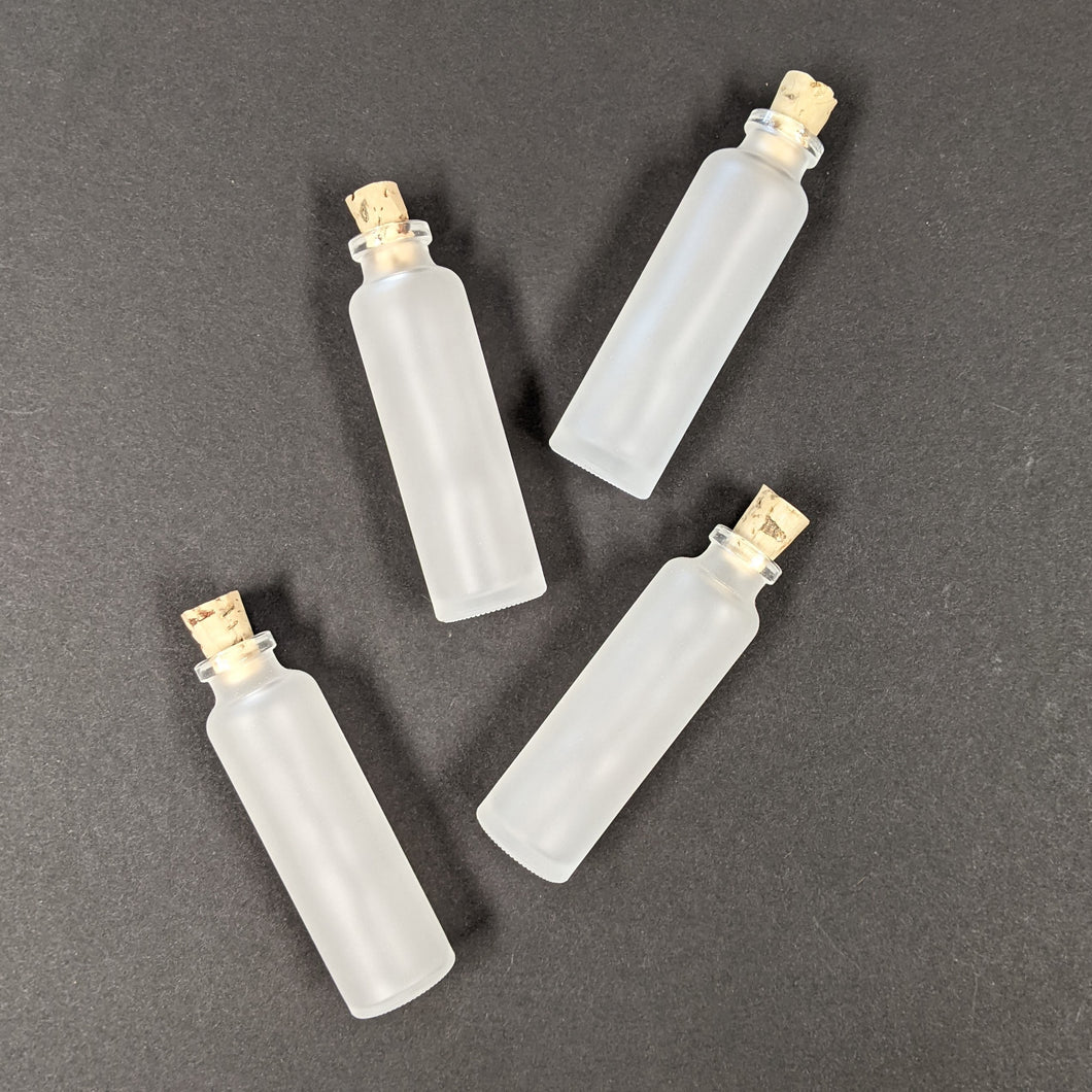 Four corked white frosted glass bottles on a black background. Sold at Coyote Supply Co a BIPOC and LGBTQIA+ owned zero waste witch store in Reno Nevada