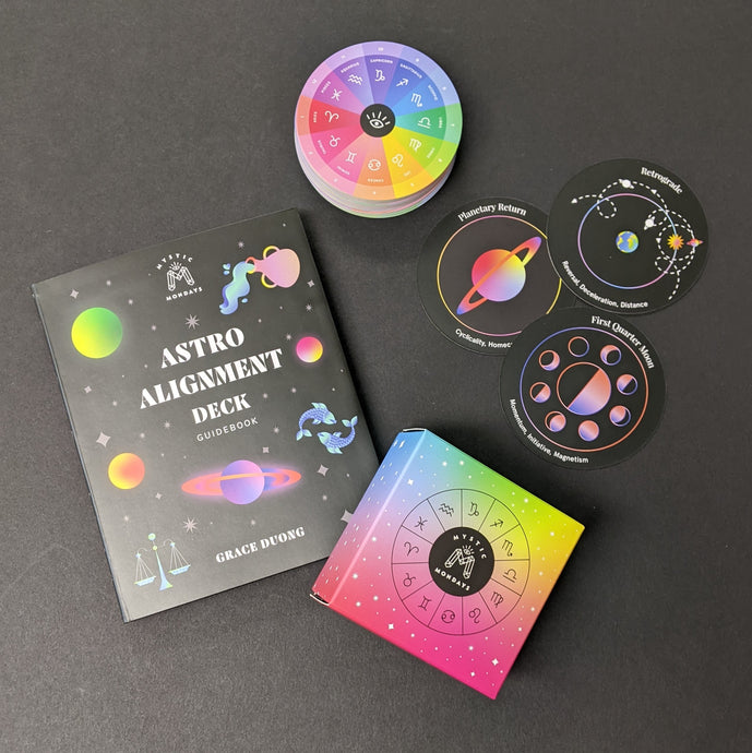 A black guide book that reads Astro Alignment Deck by Grace Duong and an assortment of round colorful cards depicting planets and astrological signs.  Sold at Coyote Supply Co a BIPOC and LGBTQIA+ owned zero waste witch store in Reno Nevada 