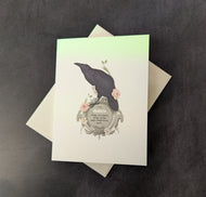 A white greeting card with an illustration of a raven sitting on a circular silver plaque with flowers around it behind the card is a white envelope all pictured on a dark background. 
The plaque reads:
The Raven
change, clairvoyance, courage, destiny, magic, manifestation, quests

This item is sold at Coyote Supply Co a BIPOC and LGBTQIA+ owned zero waste witch store in Reno Nevada