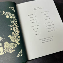 Load image into Gallery viewer, The Celtic Year book open to its table of contents pictured on a dark background.

This item is sold at Coyote Supply Co a BIPOC and LGBTQIA+ owned zero waste witch store in Reno Nevada