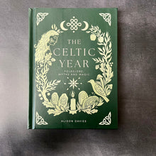 Load image into Gallery viewer, A green hardcover book on a dark background. The cover reads:
The Celtic Year
Folkelore
Myths and Magic
Alison Davies

This item is sold at Coyote Supply Co a BIPOC and LGBTQIA+ owned zero waste witch store in Reno Nevada