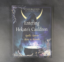 Load image into Gallery viewer, Illustrated book cover that reads 'Entering Hekate's Cauldron' by Cyndi Brannen, the cover illustration is of an hooded feminine figure over a glowing cauldron surrounded by plants on a black background.
Sold at Coyote Supply Co a BIPOC and LGBTQIA+ owned zero waste witch store in Reno Nevada