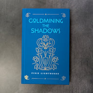 A royal blue hardcover book with a gold illustration of a big cat surrounded by flowers and crescents, the cover reads 