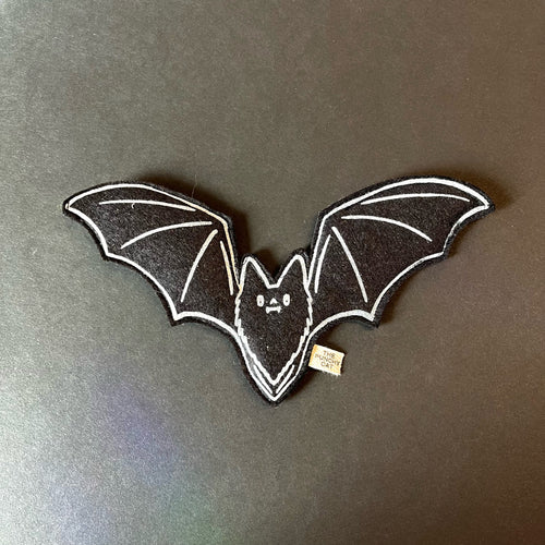 A black felt cat toy in the shape of a bat with white details printed on.
Sold at Coyote Supply Co a BIPOC and LGBTQIA+ owned zero waste witch store in Reno Nevada