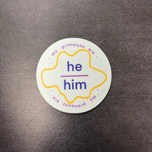 Load image into Gallery viewer, Round pronouns label sticker for he/him on a dark background.

This item is sold at Coyote Supply Co a BIPOC and LGBTQIA+ owned zero waste witch store in Reno Nevada