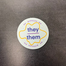 Load image into Gallery viewer, Round pronouns label sticker for they/them on a dark background.

This item is sold at Coyote Supply Co a BIPOC and LGBTQIA+ owned zero waste witch store in Reno Nevada