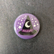 A glossy purple button with white stars and a black witch hat with a dark purple band illustration. The band of the at says 