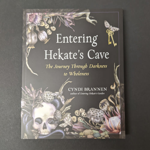 A black book cover with images of dried plants, a skull, moths, and antique keys in the center by Cyndi Brannen. Sold at Coyote Supply Co a BIPOC and LGBTQIA+ owned zero waste witch store in Reno Nevada