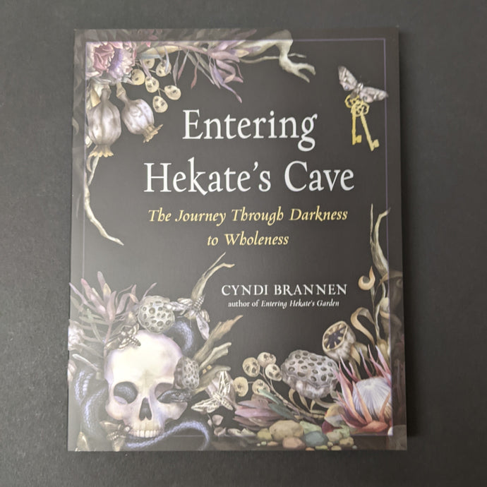 A black book cover with images of dried plants, a skull, moths, and antique keys in the center by Cyndi Brannen. Sold at Coyote Supply Co a BIPOC and LGBTQIA+ owned zero waste witch store in Reno Nevada