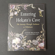 A black book cover with images of dried plants, a skull, moths, and antique keys in the center by Cyndi Brannen. Sold at Coyote Supply Co a BIPOC and LGBTQIA+ owned zero waste witch store in Reno Nevada