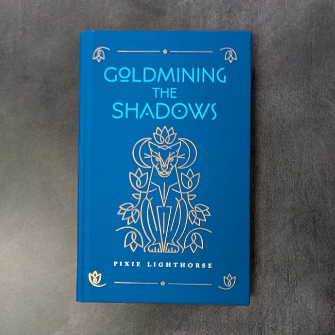 A royal blue hardcover book with a gold illustration of a big cat surrounded by flowers and crescents, the cover reads 