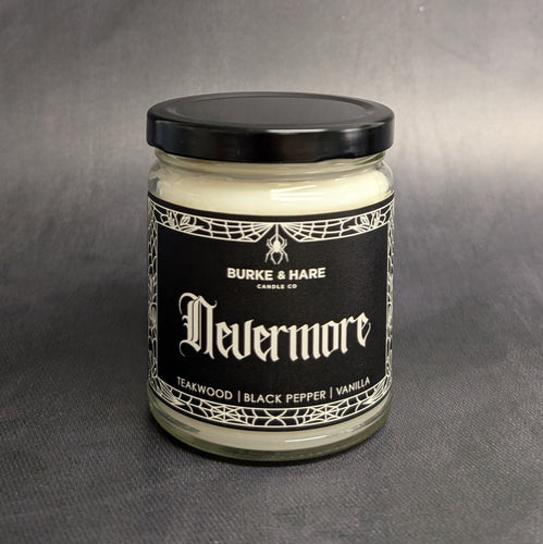 An 8oz candle with a black metal lid and a black label that reads: Burke & Hare Co Nevermore a poetic blend of teakwood, tobacco, vanilla, aand black pepper.  Sold at Coyote Supply Co a BIPOC and LGBTQIA+ owned zero waste witch store in Reno Nevada 