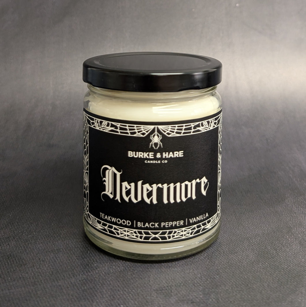 An 8oz candle with a black metal lid and a black label that reads: Burke & Hare Co Nevermore a poetic blend of teakwood, tobacco, vanilla, aand black pepper.  Sold at Coyote Supply Co a BIPOC and LGBTQIA+ owned zero waste witch store in Reno Nevada 
