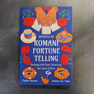 Blue book cover that reads 'Secrets of Romani Fortune Telling' by Paulina Stevens and Jezmina Von Thiele with colorful illustrations on a black background.
Sold at Coyote Supply Co a BIPOC and LGBTQIA+ owned zero waste witch store in Reno Nevada