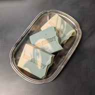 Three cream and green soap bars in a silver plate on a black background. The soap bars are stamped with the brand name Soap Distillery.

This item is sold at Coyote Supply Co a BIPOC and LGBTQIA+ owned zero waste witch store in Reno Nevada