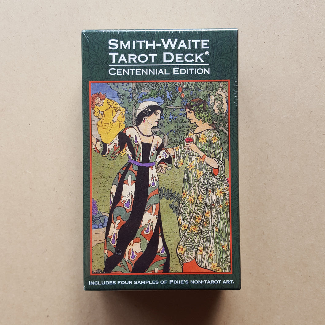 Front cover of Smith-Waite Centennial Edition tarot deck's box.  Box is bordered with dark green, text is in white, and artwork features two people in ornate flowing gowns talking, with a third person in a gown in the upper left background available at Coyote Supply Co, a zero waste witch store in Midtown Reno, Nevada that is BIPOC owned