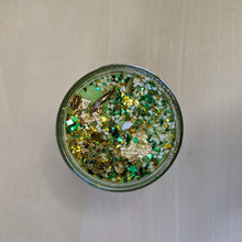 Load image into Gallery viewer, Green soy wax candle topped with glitter, sesame seeds, a penny, and gold leaf by Firme Arte available at Coyote Supply Co, a zero waste witch store in Midtown Reno, Nevada that is BIPOC owned