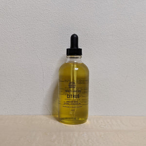 Glass bottle with black dropper lid containing golden multi use oil by Motherland Essentials reads "citrus" in black block letters available at Coyote Supply Co, a zero waste witch store in Midtown Reno, Nevada that is BIPOC owned