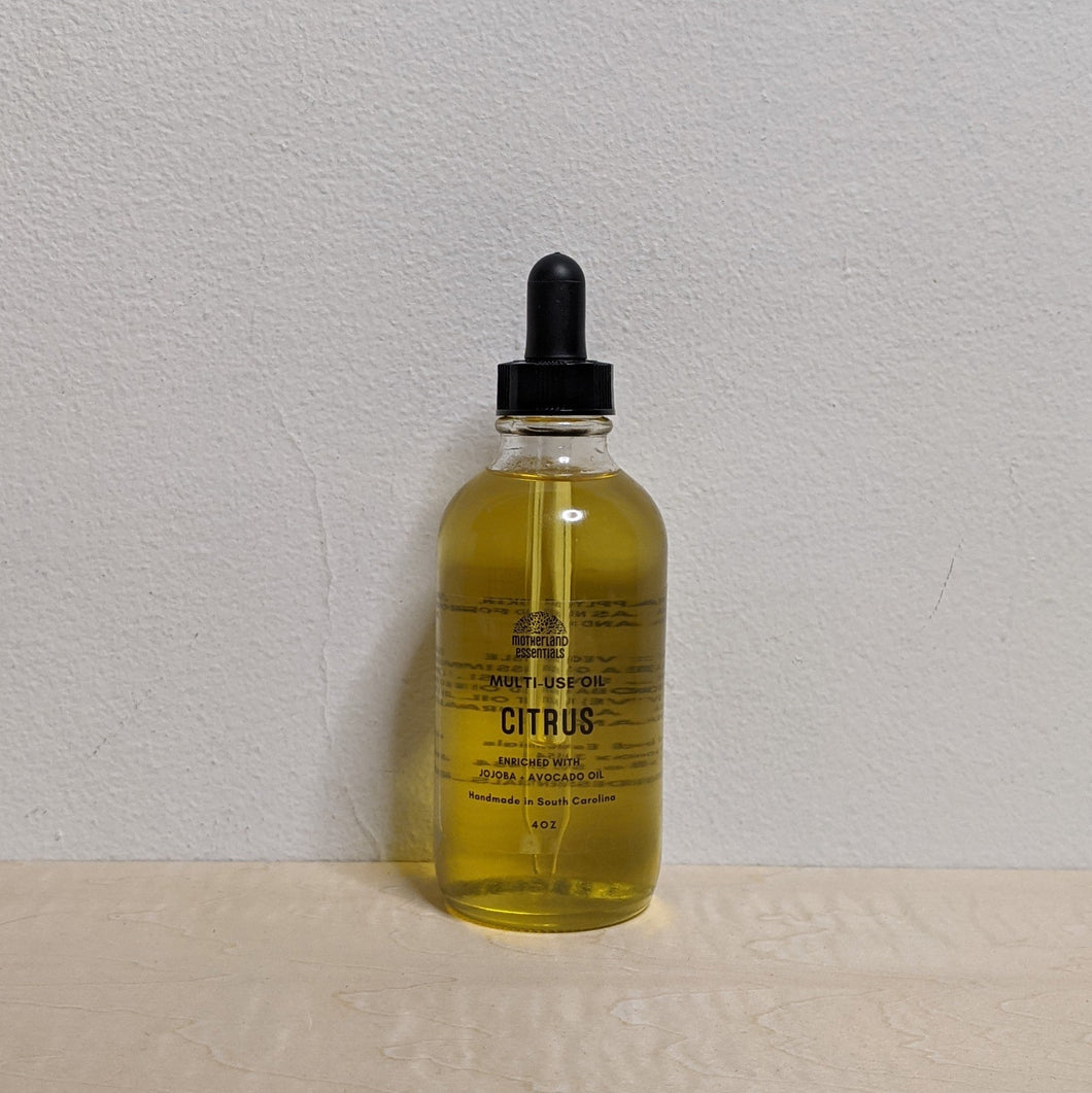 Glass bottle with black dropper lid containing golden multi use oil by Motherland Essentials reads 