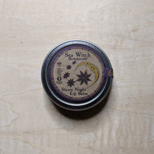 Load image into Gallery viewer, Round metal tin with round kraft paper label featuring a purple boarder &amp; a yellow crescent moon with star anise containing vegan lip balm by Sea Witch Botanicals available at Coyote Supply Co, a zero waste witch store in Midtown Reno, Nevada that is BIPOC owned