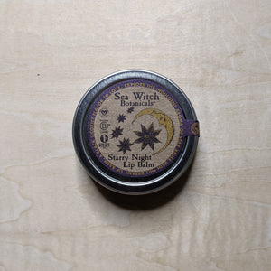 Round metal tin with round kraft paper label featuring a purple boarder & a yellow crescent moon with star anise containing vegan lip balm by Sea Witch Botanicals available at Coyote Supply Co, a zero waste witch store in Midtown Reno, Nevada that is BIPOC owned