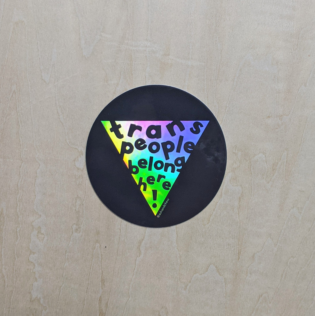 Round black sticker features a rainbow holographic triangle in the center that reads 